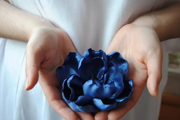 Цветок из ткани умещается в женских руках
